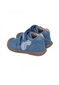 Scarpe sintetiche blu con una fascia in Velcro, caratterizzate da un design arcobaleno grigio. La suola è marrone e l'interno è di colore chiaro.