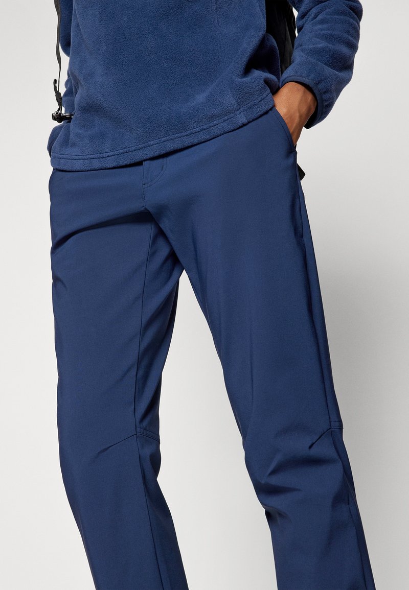 Pantalons d'extérieur bleu marine en tissu léger et extensible avec une texture lisse, dotés de poches latérales et de genoux articulés pour plus de mobilité.