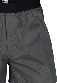 Boxer shorts a righe grigie con una cintura elastica nera e logo in rilievo. Tessuto leggero con una vestibilità ampia e tasche laterali.