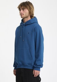 Blauwe hoodie van katoen, met een kangoeroezak, trektouwen, geribbelde manchetten en een klein zwart logo op de borst.