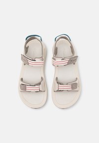 Sandalias con un upper sintético en beige y gris claro, correas ajustables con franjas rosas y blancas, y un acento en el talón de color azul sólido.