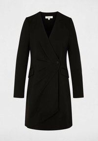 Abito nero su misura con design avvolgente, maniche lunghe, leggere pieghe e chiusura con bottoni frontali. Presenta due tasche laterali.