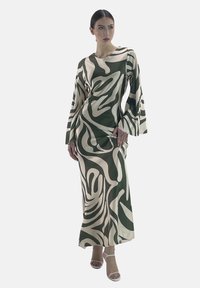 Robe à manches longues verte et crème, ornée d'un motif abstrait ondulé. Fabriquée en tissu lisse, elle présente une coupe décontractée et des manches évasées.