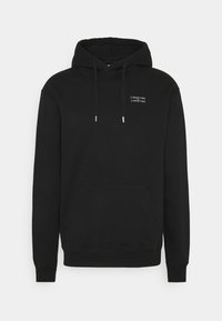 Černá mikina s kapucí vyrobená z měkké látky, s klokaní kapsou, šňůrkovou kapucí a bílým potiskem na hrudi.