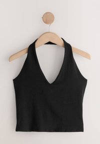 Top court noir sans manches à col halter suspendu sur un cintre en bois sur un fond clair uni.