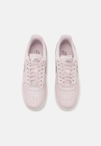 Sneakers in suede rosa chiaro con tomaia testurizzata, design con lacci, perforazioni sulla parte anteriore e suola in gomma bianca. Logo Nike argentato sul lato.