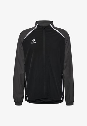 Zwarte sportjack met grijze accenten, ritsluiting, opstaande kraag en elastische manchetten. Bevat logo op de borst en zijstrepen.