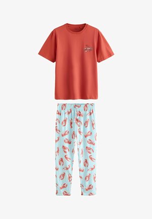 Top cu mâneci scurte în culoarea ruginii, cu grafică de homar și textul „wild cancer”, asortat cu pantaloni cu dungi albastru deschis, decorați cu imprimeuri de homari roșii pe toată suprafața.