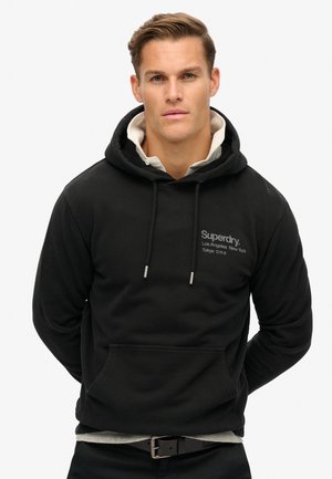 Black hoodie made of cotton blend, with a front pocket, drawstring hood, and white logo detail on the chest. Casual fit, textured fabric.