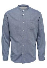 Pitkähihaisissa, nappikiinnitteisessä paidassa on sinistä chambray-kangasta ja kaulukseton muotoilu. Paidassa on rintatasku ja valkoiset napit edessä.