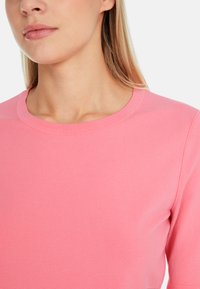 Pink knitted sweater with a crew neckline and short sleeves. The fabric appears soft with a smooth texture and minimal seams.