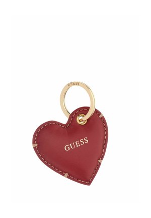 Llavero de cuero rojo en forma de corazón con costuras beige y anilla dorada, nombre de la marca Guess impreso en letras doradas en el corazón.