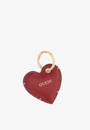 Llavero de cuero rojo en forma de corazón con costuras beige y anilla dorada, nombre de la marca Guess impreso en letras doradas en el corazón.