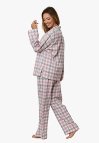 Dwuczęściowa piżama w kratkę w kolorach różowym, szarym i białym. Bluzka zapinana na guziki z długimi rękawami; luźne spodnie w podobny wzór. Miękka faktura tkaniny.
