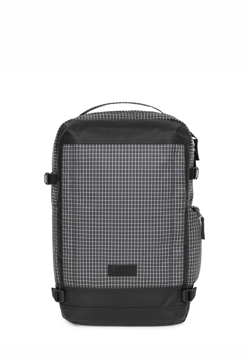 Sac à dos à motifs damiers noir et blanc avec une finition lisse, doté de sangles latérales, d'une poignée supérieure et d'une base noire. Étiquette de marque notable sur le devant.