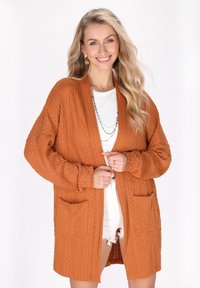 Cardigan lavorato a maglia di colore arancione bruciato, con apertura frontale, maniche lunghe, due tasche frontali e un motivo testurizzato.