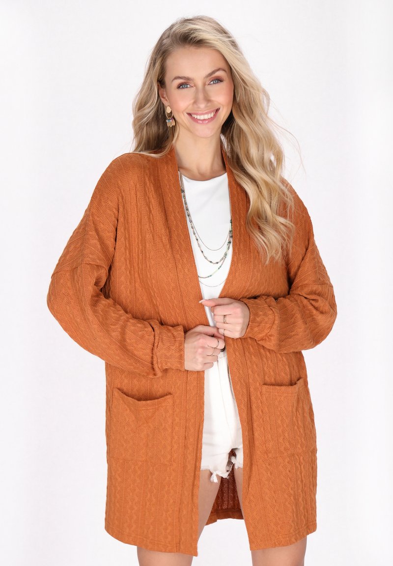 Cardigan lavorato a maglia di colore arancione bruciato, con apertura frontale, maniche lunghe, due tasche frontali e un motivo testurizzato.