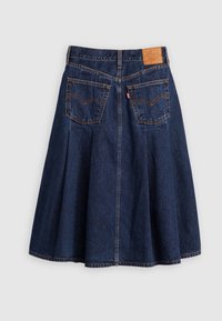 Falda de mezclilla con diseño plisado, color azul oscuro, dos bolsillos traseros y una etiqueta de cuero en la cintura que presenta el logotipo y los detalles de la marca.