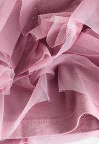 Hellrosa Tüllstoff mit weicher Textur, der mit verstreuten goldenen Punkten und eleganten Rüschen versehen ist. Die Kanten sind ordentlich genäht für Langlebigkeit.