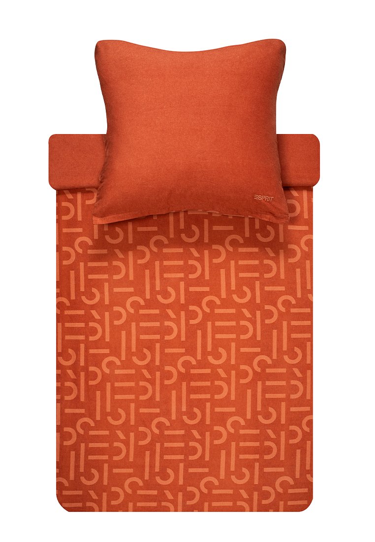 Ensemble de literie orange avec un coussin texturé uni et une housse de couette à motifs présentant un design géométrique dans une teinte plus claire d'orange.