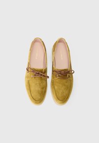 Veluurist loafersid sinepikollases toonis, ümara varbaosaga, pruunide paelte ja helepruuni kummist tallaga. Sisemine vooder on heleroosa logoga detailidega.