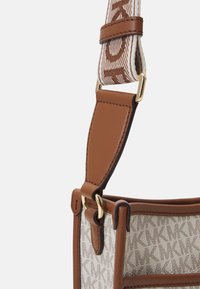 Brun lædertaske rem med et vævet mønster. Har guldhardware, en glat tekstur og en tan farve, som forbedrer den samlede struktur.