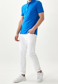 Modrá polo košile s bílým lemem, doplněná bílými kalhotami a bílými teniskami. Polo má knoflíkovou lištu a krátké rukávy.