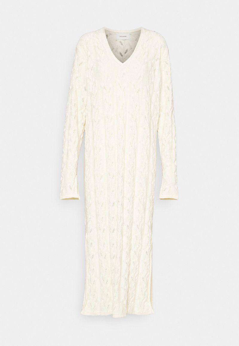 Robe en maille de couleur crème avec un col en V et des manches longues. Présente un motif en maille torsadée texturée. Longueur mi-cuisse avec une coupe droite.
