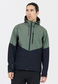 Vandtæt jakke med et tofarvet design; øverste del er grøn og nederste del er navy. Den har hætte, frontlynlås og to sidelommer.