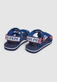 Modré sandály s textilními pásky, s páskem s logem a červenými detaily. Texturovaná stélka, stylizované bílé pruhy na mezipodešvi.