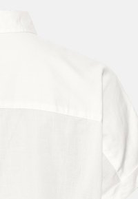 Weißes Hemd mit sichtbarem Kragen und weicher Textur, das ein schlichtes Design und leichtes Material präsentiert, von hinten betrachtet.