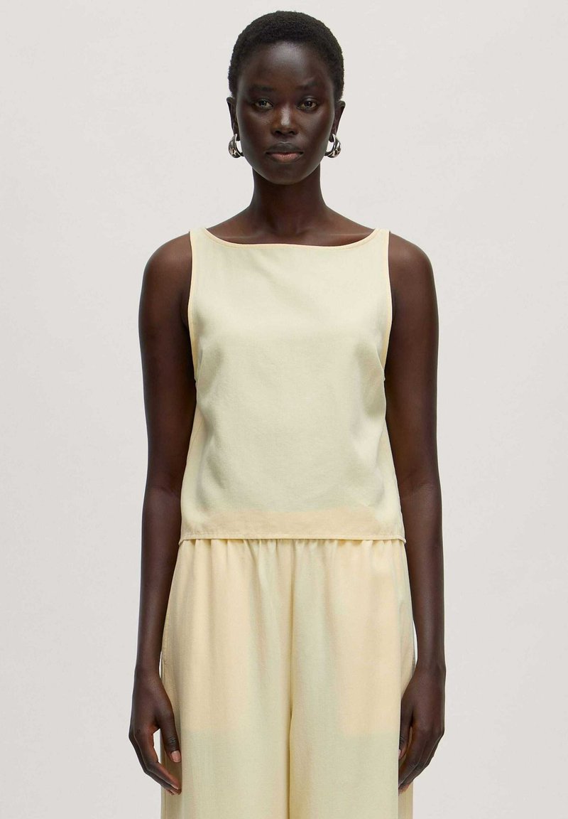Hellgelbes, ärmelloses Top aus weichem Material, mit quadratischem Ausschnitt, geradem Schnitt und subtiler Textur, kombiniert mit passenden Hosen.