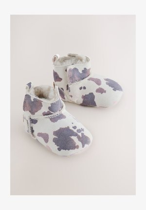 Bijele i blijedo ljubičaste dječje čizme s uzorkom kravljeg printa, mekanim unutarnjim oblogom i kopčom na strani. Zaobljeni vrh i plišana tekstura.