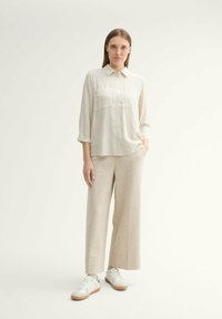 Lightly striped button-up shirt with front pockets, paired with beige wide-leg pants and white sneakers with beige accents.