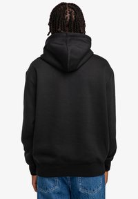 Black hooded sweatshirt made from soft, thick fabric. Features a kangaroo pocket and ribbed cuffs. Minimalist design with no graphic prints.
