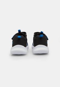 Par av svarta och blåa träningsskor med vita sålar, visade bakifrån på en vit bakgrund.