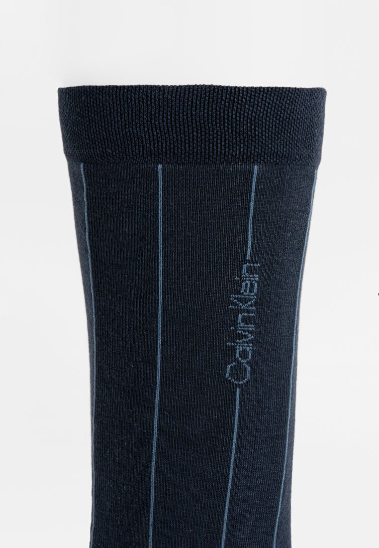 Dunkelblauer Socken mit geripptem Bund, versehen mit hellblauen vertikalen Streifen und gesticktem "Calvin Klein"-Logo an der Seite.