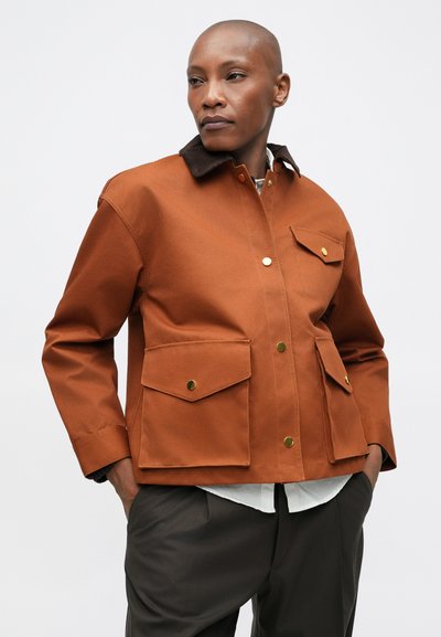 Barna vászon dzseki sötét gallérral, arany gombokkal és két tágas első zsebbel. Laza szabású és egyenes fazonú.