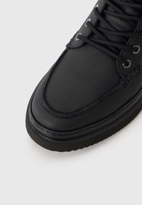 Pantof black din piele cu o finisare texturată, vârf rotunjit și șireturi negre. Prezintă o talpă din cauciuc și detalii cusute de-a lungul marginilor.