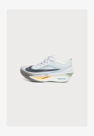Chaussure de course Nike Zoom Fly blanche et grise avec un swoosh noir, des lacets blancs et une semelle épaisse avec le marquage « zoomx » sur le côté.