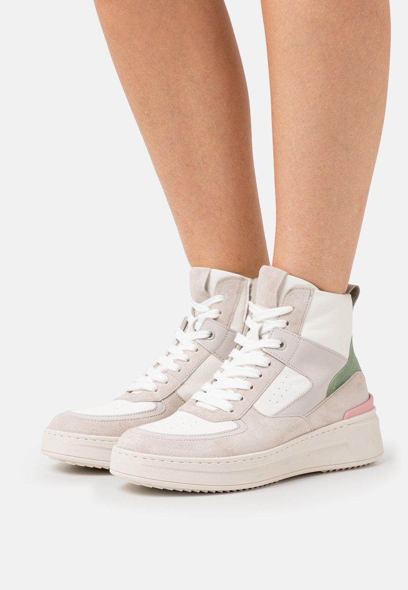 High-top sneakers in beige, white, and pastel green. Made of leather and suede with a textured sole and lace-up design.