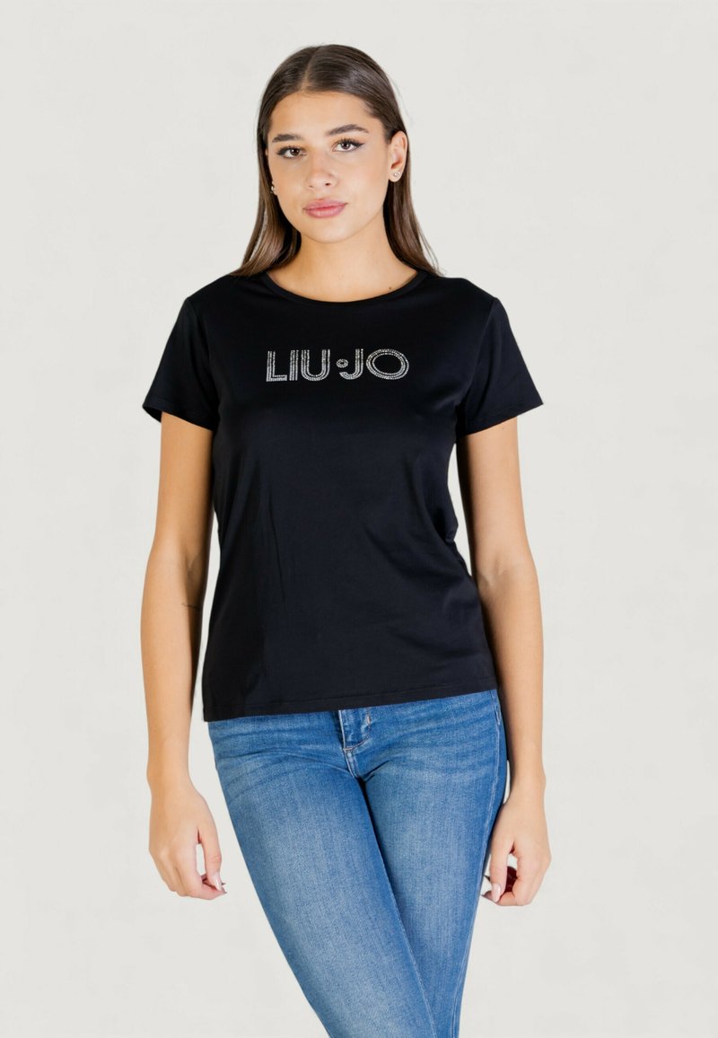 T-shirt noir à manches courtes en tissu lisse avec le logo "LIU·JO" en strass sur la poitrine ; porté avec un jean en denim bleu.