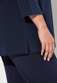 Navyfarbene Tunika mit lockerer Passform, features Dreiviertelärmel und Seitenschlitze. Glattes Baumwollmaterial mit leichtem Glanz.