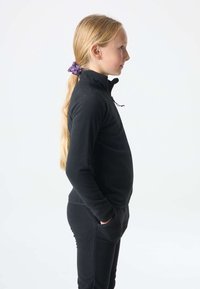 Czarny polarowy sweter z wysokim kołnierzem i półzamkiem, w zestawie z dopasowanymi polarowymi spodniami, które mają boczne kieszenie. Gładka tekstura.
