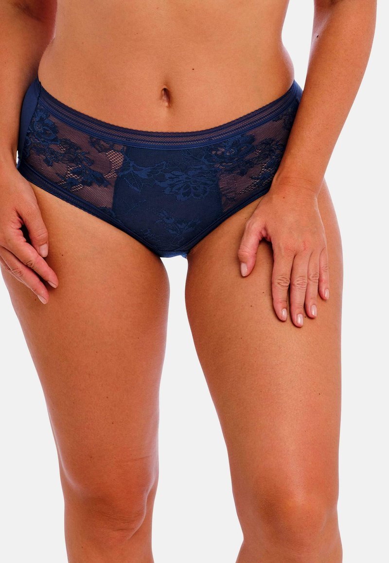 Marineblauwe hooggetailleerde slips met bloemend kant, met een zachte tailleband en een zachte textuur. Accenten van doorschijnende details aanwezig.