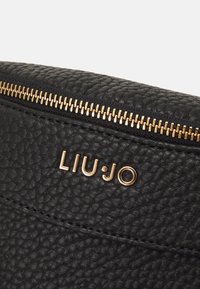 Schwarze, strukturiert Lederhandtasche mit goldenem Reißverschluss und Beschlägen. Mit eingraviertem Markennamen "LIU·JO", der prominent angezeigt wird.