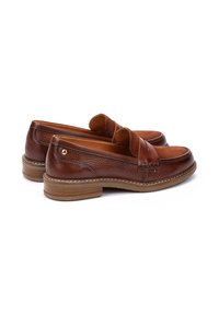 Mocasines de piel marrón con acabado texturizado, suela de goma y costuras decorativas. Punta redondeada y pequeño acento metálico en el talón.