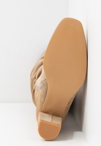Bota de ante beige con una textura suave, punta redondeada y suela de goma plana y estriada. Cuenta con una cremallera lateral para facilitar su uso. Talla 37 marcada.