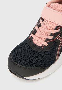 Baskets de sport noires et roses avec tige en mesh, fermeture à lacets et col rembourré. Caractéristiques d'une semelle lisse et de lignes d'accent subtiles.
