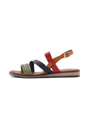 Sandalia plana con correas trenzadas en verde oliva y negro, tira de cuero roja con hebilla en el tobillo y suela marrón con tacón bajo.